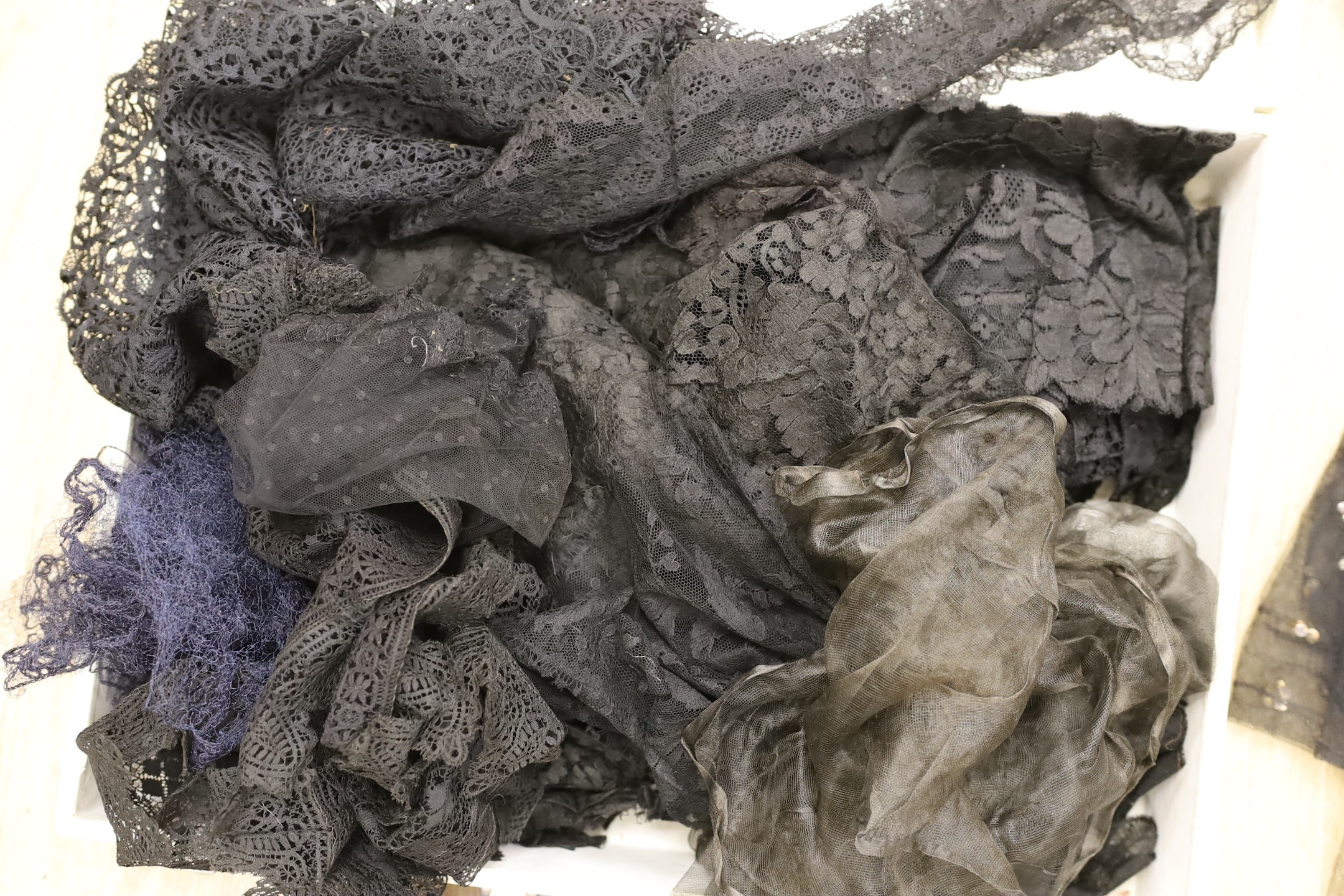 A suitcase of mixed 19th and 20th century black machine and bobbin laces, servants bonnets, cream lace, etc